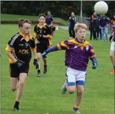  ??  ?? Joseph Tomkins of St. Patrick’s keeps his eye on the ball as Dylan Hendy (Réalt na Mara) gives chase.