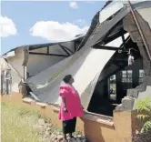  ?? /ANTONIO MUCHAVE ?? Lucy Kgwedi inspects the damaged roof and the wall of the school.