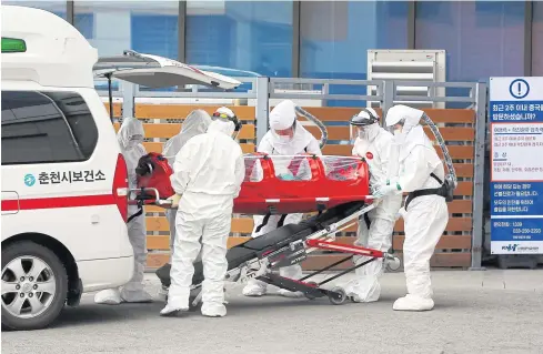  ??  ?? TAKING PRECAUTION­S: Medical workers wearing protective gear carry a patient infected with Covid-19 at a hospital in Chuncheon, South Korea yesterday. South Korea reported 229 more coronaviru­s cases of Covid-19 yesterday, the sharpest spike in infections yet outside China.