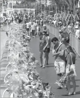  ?? CLAUDE PARIS, THE ASSOCIATED PRESS ?? People look at flowers and messages placed along the beach of the Promenade des Anglais in Nice, in southern France where dozens were killed in last week’s Bastille Day truck attack.