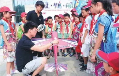  ?? YUAN JINGZHI / FOR CHINA DAILY ?? A teacher shows a model aircraft to the children of rural migrant workers during a summer camp at Northwest Polytechni­cal University in Xi’an, Shaanxi province, on Monday. The children planned to visit a museum and an ocean park, and to attend training...