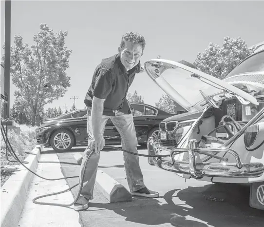  ?? IRFAN KHAN/LOS ANGELES TIMES ?? Mark Wagner, who converted his 1962 VW Beetle ragtop from gas to electric, charges it April 19 at a charging station in Irvine, California.