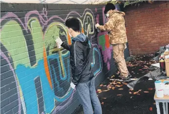  ??  ?? Members of the Ten10 youth group creating the street art message outside the church on Brancepeth Road.