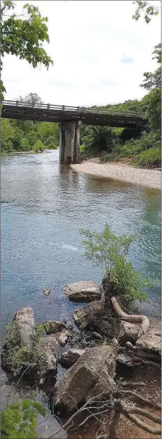  ?? Courtesy of Xyta Lucas ?? Pieces of concrete, presumably from the abutment of the old iron truss bridge, are visible in the foreground with the present bridge visible in the distance.