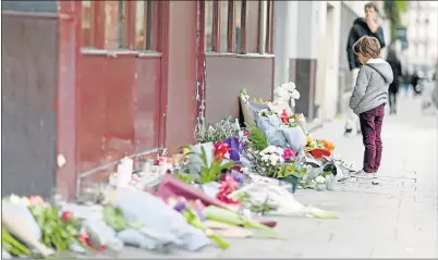  ?? Picture: PIERRE SUU/GETTY IMAGES ?? CAPITAL SORROW: A boy looks at floral tributes in front of Le Carillon restaurant at the weekend in Paris. At least 129 people were killed and more than 200 injured, 80 seriously, following a series of terrorist attacks in the French capital