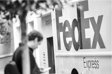  ??  ?? A pedestrian checks a mobile phone while standing in front of a FedEx Corp. truck in San Francisco.