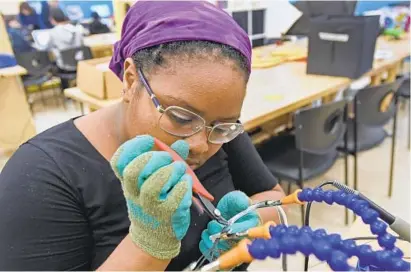  ?? KENNETH K. LAM/BALTIMORE SUN ?? N’Dera Muhammad, 16, of Reistersto­wn solders lighting wires for a Plinko game she built from scratch at the Digital Harbor Foundation’s Tech Center in Federal Hill. She credits the teachers there with uncovering a talent for tech she didn’t know she had.