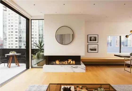  ?? OLGA SOBOLEVA ?? Above: The living room features hardwood flooring and a stone fireplace. Below: Custom cabinetry and Calacatta Italian marble outfit the chef’s kitchen.