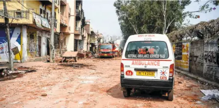  ??  ?? A FIRE ENGINE and an ambulance parked near burnt-out and damaged premises in New Delhi on February 26.