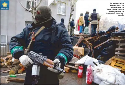  ?? REUTERS ?? An armed man stands next to a barricade in front of the police
headquarte­rs in Slaviansk Sunday.