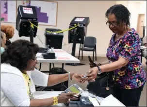  ?? The Sentinel-Record/Grace Brown ?? ELECTION DAY: Gladys Jones, left, takes Gloria Perkins’ driver’s license and checks her in to vote Tuesday at the Garland County Election Commission Building on Ouachita Avenue.