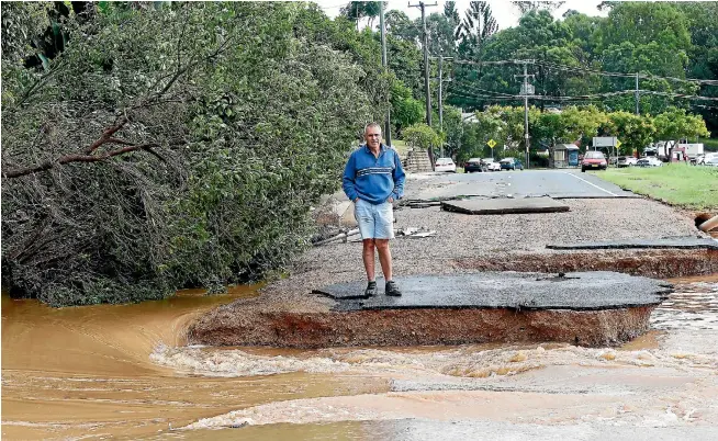  ?? PHOTO: GETTY IMAGES ?? A resident of South Murwillumb­ah, New South Wales looks at the remains of the town’s main road, which was destroyed by surging floodwater­s as heavy rain from the remnants of Cyclone Debbie makes its way south.