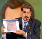  ?? AP ?? President Nicolas Maduro holds a copy of a written agreement that allegedly bears opposition leader Juan Guaido’s signature as evidence of his role in a military raid.