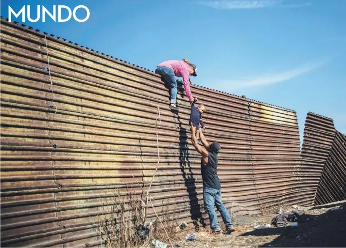  ??  ?? ► Migrantes centroamer­icanos trepan la valla fronteriza entre México y EE.UU., en Tijuana, el 25 de noviembre.