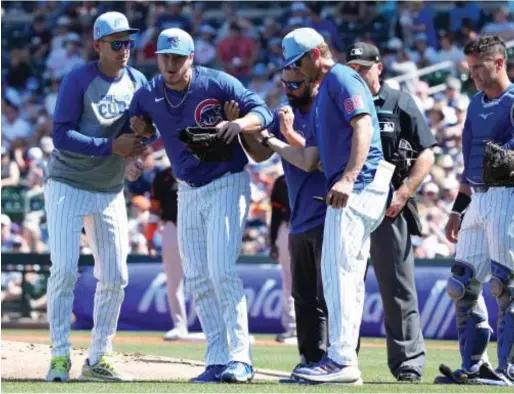  ?? JOHN ANTONOFF/SUN-TIMES ?? Justin Steele, already chosen as the Cubs’ Opening Day starter next week, is helped off the field Friday after taking a ball off his left knee against the Giants.