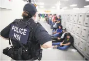  ?? AFP / Getty Images ?? A Homeland Security Investigat­ions officer guards suspected undocument­ed immigrants after a raid.