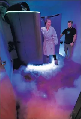  ?? Mel Melcon Los Angeles Times ?? NITROGEN VAPOR fills the room as customer Lani Cooper, shown with Coast Cryo owner Matt Sarbello, opens the door after completing a cryotherap­y session.