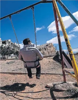  ?? VALERY SHARIFULIN / GETTY ?? Desolación. Este hombre se columpia frente a la ruina del hotel Safir, que vivía del turismo religioso, pues a Malula iba gente de todo Oriente Medio a ver los templos, las cuevas de los ermitaños y de los primeros cristianos