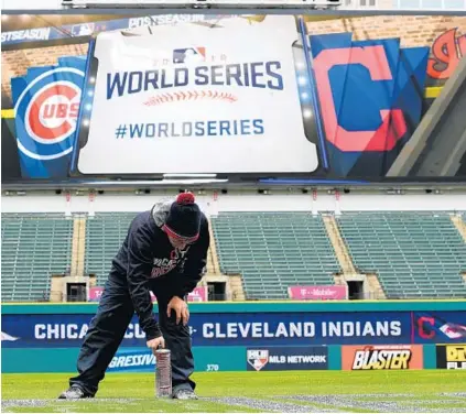  ?? JASON MILLER/GETTY IMAGES ?? A member of Cleveland’s grounds crew paints the World Series logo on the field Monday in preparatio­n for Game 1 of the World Series between the Indians and Cubs tonight. The Cubs last won the World Series in 1908. The Indians’ last World Series win...