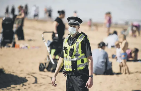  ??  ?? 0 A police officer patrols on Edinburgh’s Portobello beach as the hottest day of the year so far brought crowds out in anticipati­on of an easing of lockdown rules