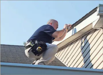  ??  ?? BELOW: As part of a home inspection, John Caldwell takes a detailed look roof shingles.