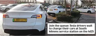  ?? ?? Join the queue: Tesla drivers wait to charge their cars at South Mimms service station on the M25