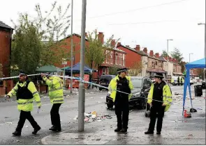  ?? AP/PETER BYRNE ?? Police officers stand at the scene on Claremont Road in Manchester after a shooting Sunday.