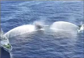  ?? (AP/Philippine Coast Guard) ?? Philippine resupply vessel Unaizah, center, is hit by two Chinese coast guard water cannon blasts, causing injuries to multiple crew members as they tried to enter the Second Thomas Shoal, locally known as Ayungin Shoal, in the disputed South China Sea, on Tuesday.