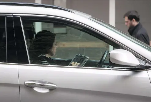  ?? — CP FILES ?? A woman uses an iPad while behind the wheel. Fewer drivers are being ticketed for distracted driving.