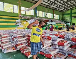  ??  ?? HANDS ON Mayor Garandy Danao helps distribute relief packs among the citizens of Narra, Palawan; right: Narra residents working together to make sure every family will receive supplies from the local government