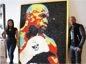  ??  ?? Floyd Mayweather poses next to a portrait of himself and the artist Tiffanie Anderson