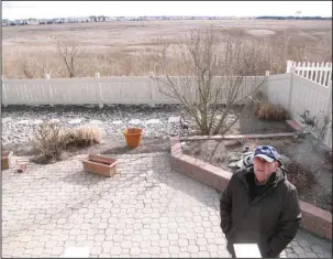  ?? The Associated Press ?? SMALL TRICKLE: Marty Mozzo stands in his backyard Feb. 16 in Ocean City N.J. on the edge of a back-bay wetlands. When he and his wife were considerin­g buying the house, they looked at a small trickle of water in the distance and wondered if the...