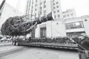  ?? Diane Bondareff / Associated Press ?? Workers prepare to raise the 2018 Rockefelle­r Center Christmas tree, a 72-foot tall, 12-ton Norway Spruce from Wallkill, N.Y., on Saturday in New York City.
