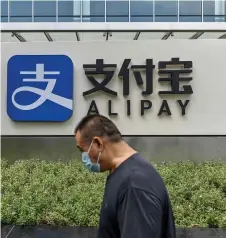  ?? — AFP file photo ?? A pedestrian walking past an Alipay logo at the Shanghai office building of Ant Group in Shanghai.