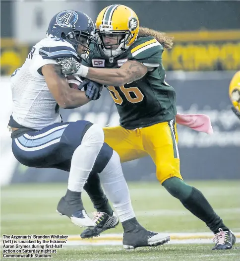  ?? JEFF McINTOSH/THE CANADIAN PRESS ?? The Argonauts’ Brandon Whitaker (left) is smacked by the Eskimos’ Aaron Grymes during first-half action on Saturday night at Commonweal­th Stadium.