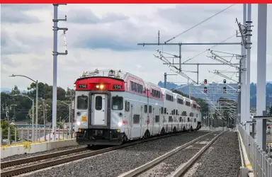  ?? Christophe­r Blaise ?? Caltrain cab car No. 114 leads train 233 at San Bruno. The catenary supports are up awaiting wire in this May 2019 view. Revenue operations with new electric-powered equipment are expected to commence in late 2024.