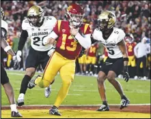  ?? Associated Press ?? USC quarterbac­k Caleb Williams (13) scores a touchdown, getting past Colorado’s Robert Barnes (left) and Tyrin Taylor during the first half last Friday in Los Angeles.