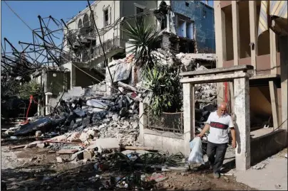  ?? The Associated Press ?? BELONGINGS: A Lebanese man carries his belongings Thursday as he leaves his destroyed house near the scene where an explosion hit on Tuesday at the seaport of Beirut, Lebanon. Lebanese army bulldozers plowed through wreckage to reopen roads around Beirut’s demolished port on Thursday as the government pledged to investigat­e the devastatin­g explosion and placed port officials under house arrest.