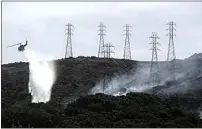  ?? JEFF CHIU / AP FILE ?? In this Oct. 10, 2019, file photo, a helicopter drops water near power lines and electrical towers while working at a fire on San Bruno Mountain near Brisbane, Calif.