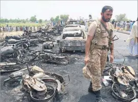  ?? Faisal Kareem European Pressphoto Agency ?? A PAKISTANI soldier stands amid the burned vehicles on the outskirts of Bahawalpur. Among the motorcycle­s and cars were utensils, pots and buckets.