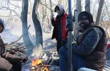  ??  ?? Homeless men huddle by a fire at a homeless camp along the Merrimack River in Lowell.