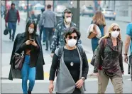  ?? ERIC RISBERG/AP PHOTO ?? In this Friday, Nov. 9, 2018, file photo, people wear masks while walking through the Financial District in the smoke-filled air in San Francisco, as authoritie­s issued an unhealthy air quality alert for parts of the San Francisco Bay Area as smoke from a massive wildfire drifts south.