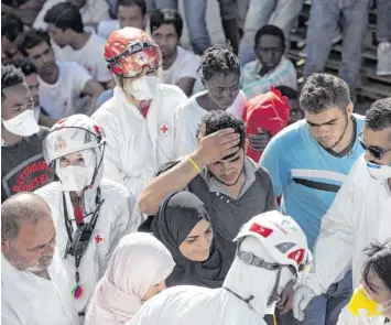  ?? Foto: Y. Nardi, dpa ?? Mitarbeite­r des Roten Kreuzes kümmern sich um Migranten, die am 20. August nach ihrer Seerettung im italienisc­hen Trapani landen. Doch nicht alle Flüchtling­e, die von Libyen aus Europa erreichen wollten, überlebten.