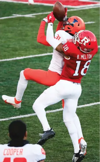  ?? COREY PERRINE/ GETTY IMAGES ?? Cornerback Devon Witherspoo­n hauls in one of Illinois’ three intercepti­ons in front of Rutgers’ Bo Melton during the Illini’s victory Saturday in Piscataway, N. J.