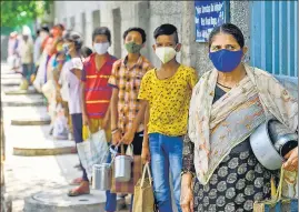  ??  ?? People wait for free cooked meals at a distributi­on centre in New Delhi on Thursday.