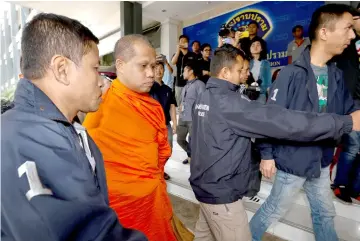  ??  ?? An unidentifi­ed assistant abbot of Golden Mount Temple is escorted by police officers at the Thai Police Crime Suppressio­n Division headquarte­rs in Bangkok.— Reuters photo