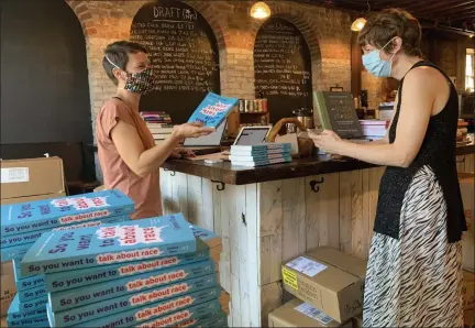  ??  ?? Kate Rosko of Saugerties, N.Y., picks up her copy of Ijeoma Oluo’s “So You Want to Talk About Race” at Rough Draft Bar and Books in Kingston, N.Y., from co-owner Amanda Stromoski.