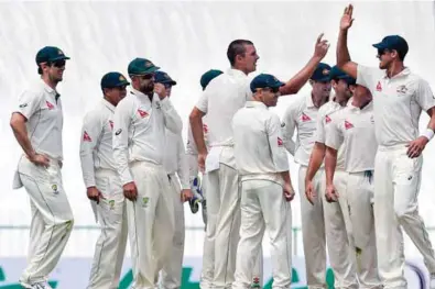  ?? – AP/PTI ?? EVENTFUL DAY: Australian teammates congratula­te their bowler Josh Hazlewood, centre, for taking one of his three Sri Lankan wickets on Day One of the first Test cricket match against Sri Lanka in Pallekele.