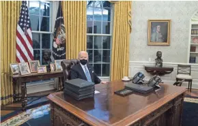  ?? EVAN VUCCI/AP FILE ?? Mask in place, in contrast to his predecesso­r, President Joe Biden prepares to sign a series of executive orders in the Oval Office on Jan. 20.