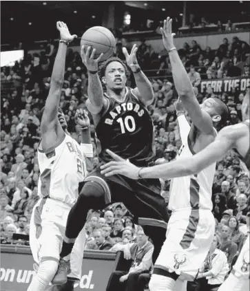 ?? Dylan Buell Getty Images ?? DeMAR DeROZAN of the Raptors works his way between Tony Snell (21) and Greg Monroe of the Bucks in the third quarter of Game 6. DeRozan scored 32 points to help Toronto advance to the second round.